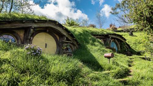 building landscape photography of brown wooden house with trees around hobbiton movie set
